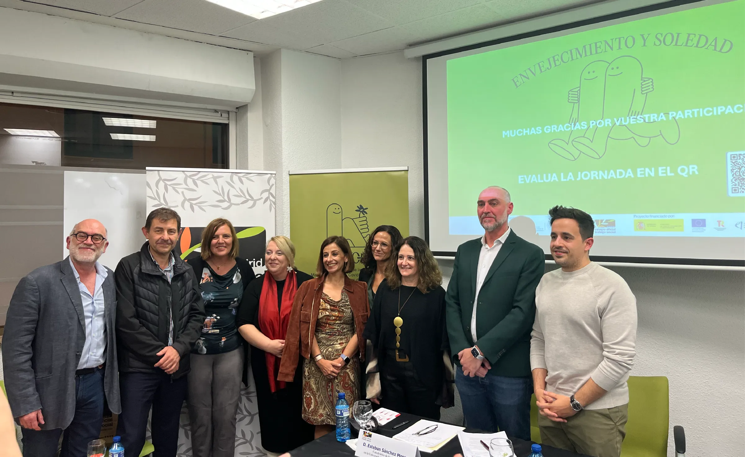 Ponentes y organizadores de la jornada Envejecimiento y soledad delante del roll-up del proyecto